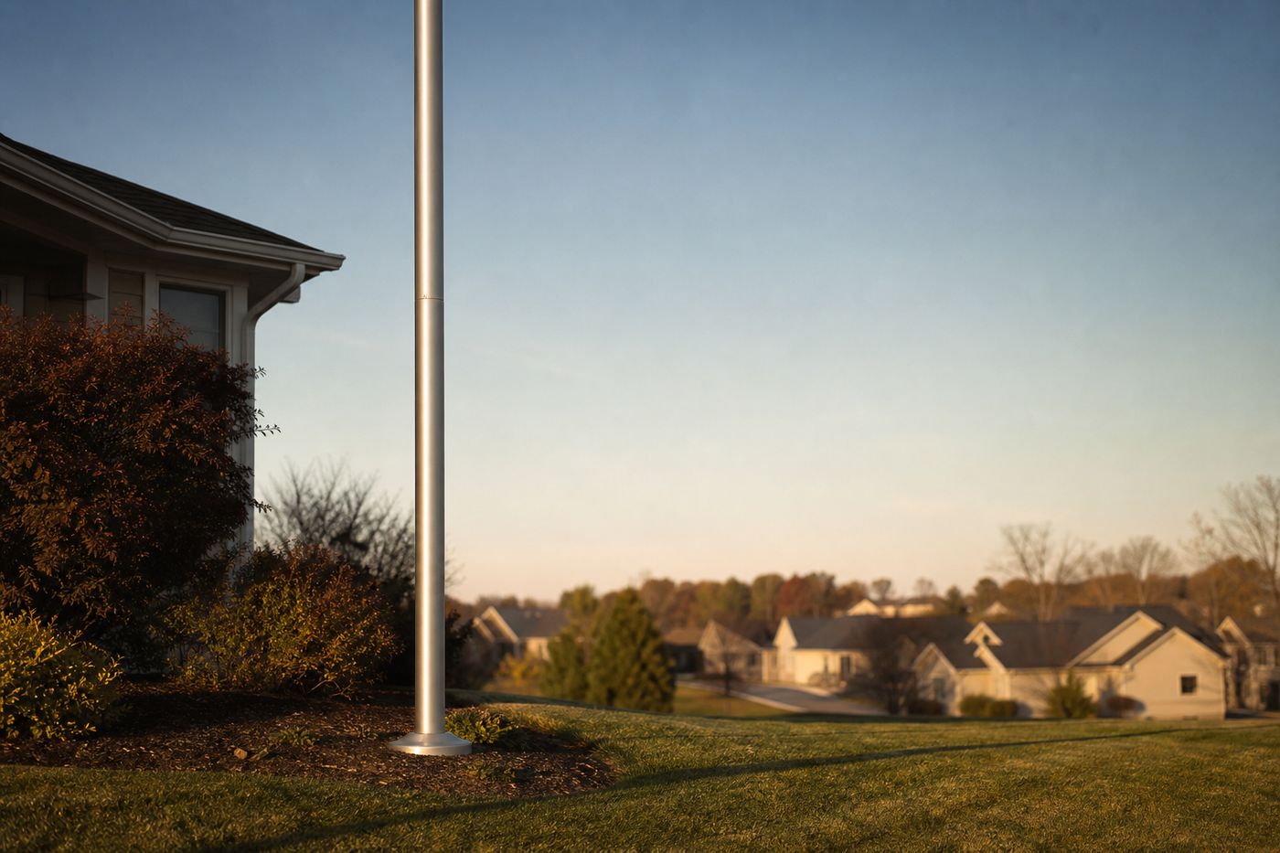 A tall American flagpole standing in a suburban front yard beside a brick home, with an HOA violation notice taped to the mailbox.